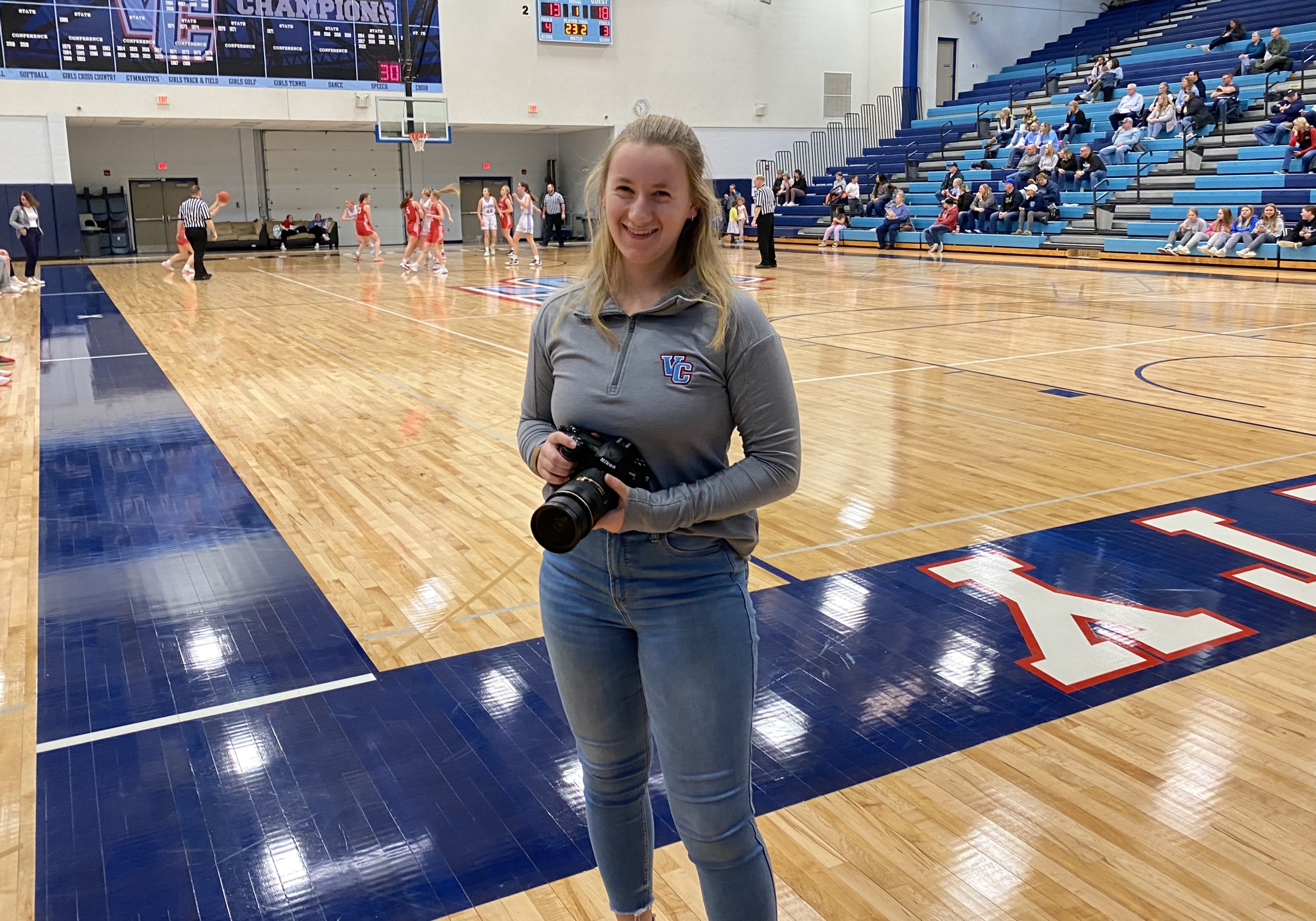 Alyssa Thomsen smiling at the camera holding a camera