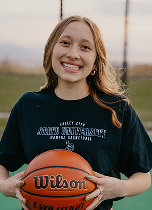 Avery Backus holds a basketball while wearing a black VCSU women's basketball t-shirt.