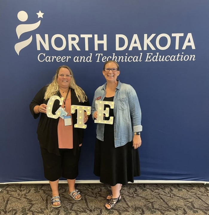 Aberle and Richman standing in front of NDCTE sign holding light up letters spelling "CTE"
