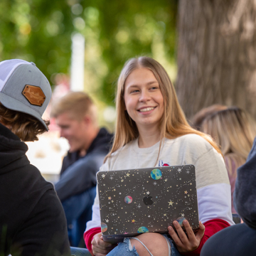 Female student with laptop talking to other student