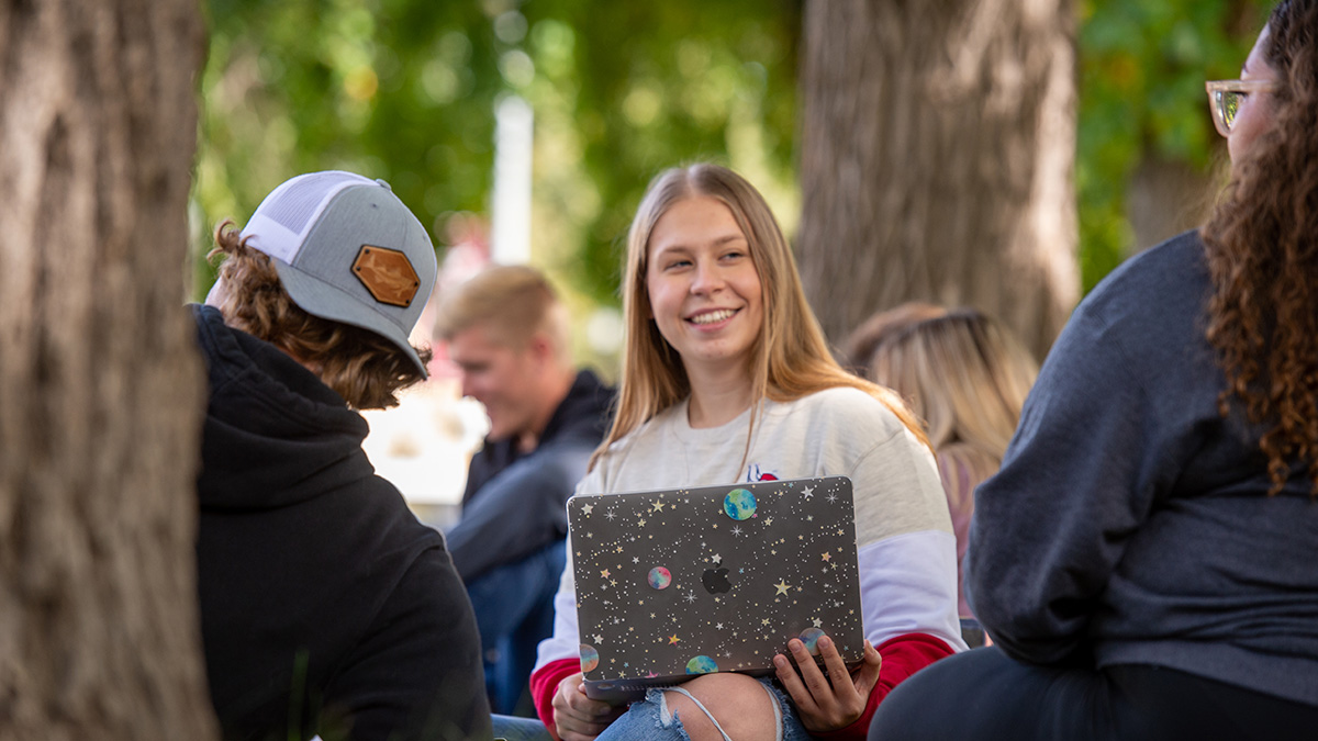 Female student with laptop talking to other student
