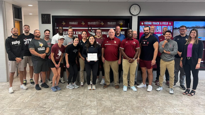 Kathleen posing with athletics staff
