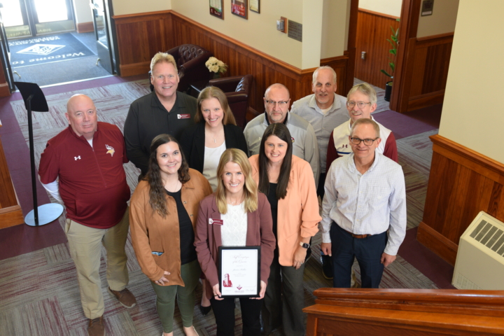 Janna Kohler holding award, surrounded by members of President's Cabinet