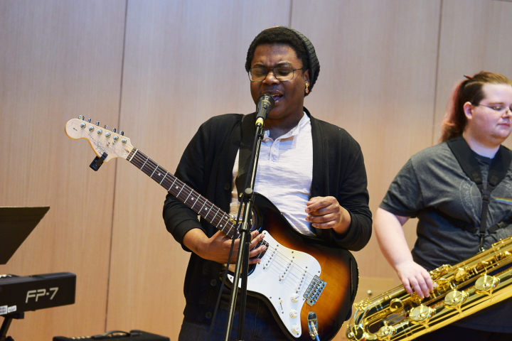 male student playing guitar/singing