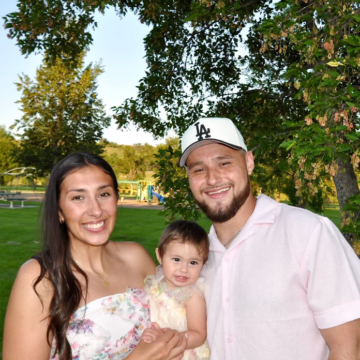 Justin Cruz smiling at the camera with his wife and daughter