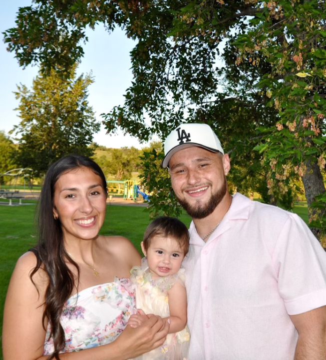 Justin Cruz smiling at the camera with his wife and daughter