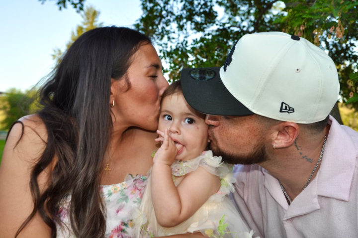 Photo of Justin Cruz and his wife kissing their daughter on the cheek