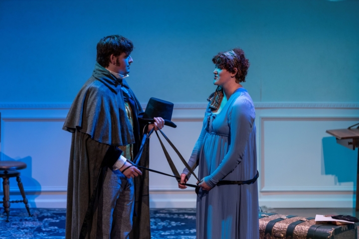 scene from a play; man and woman are facing each other, speaking and holding a rope