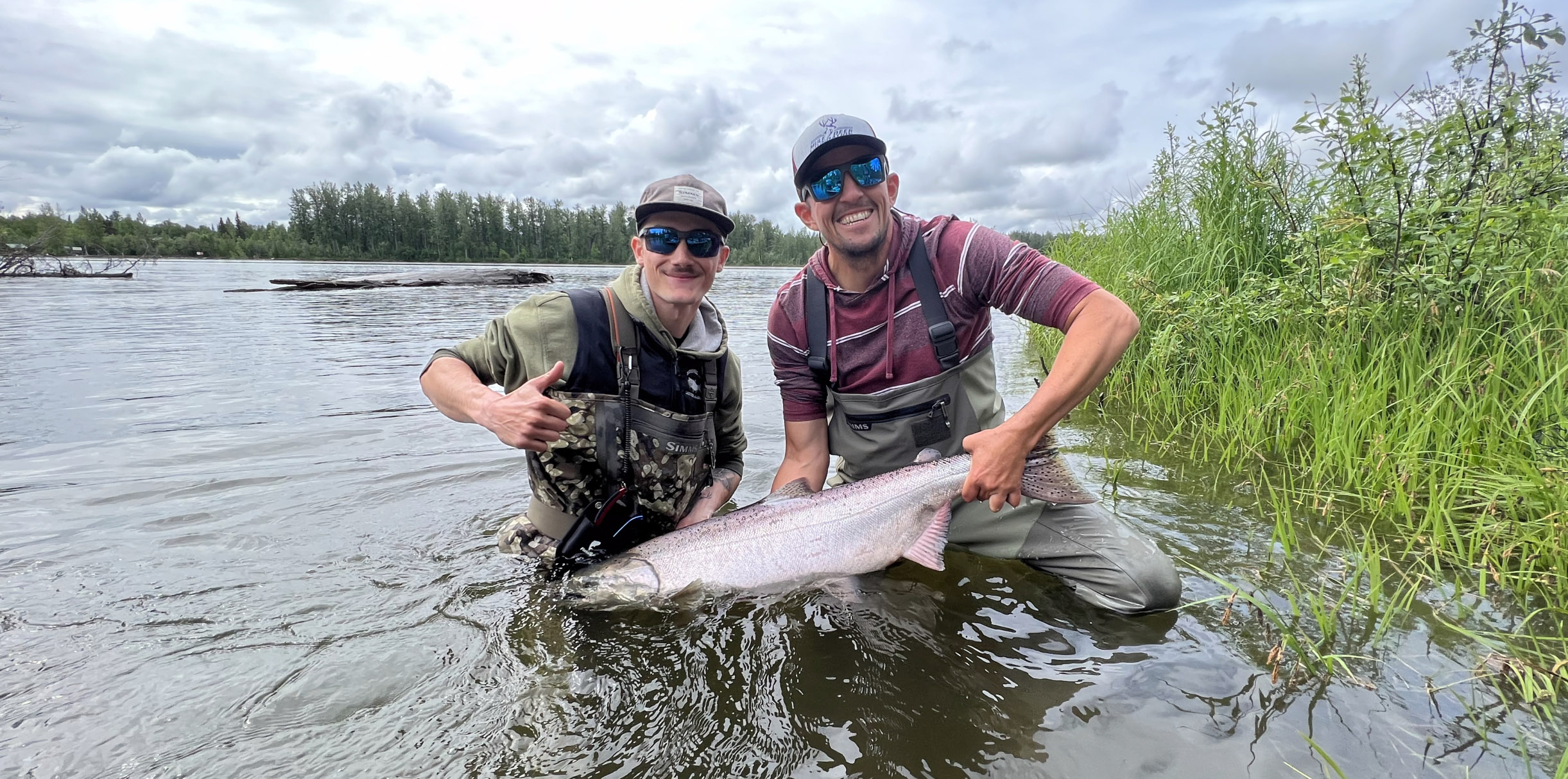 Photo of Dylan Kibel and male mentor holding a fish and smiling at the camera