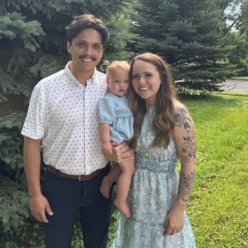 Sydni Smith smiling at the camera with her husband and daughter