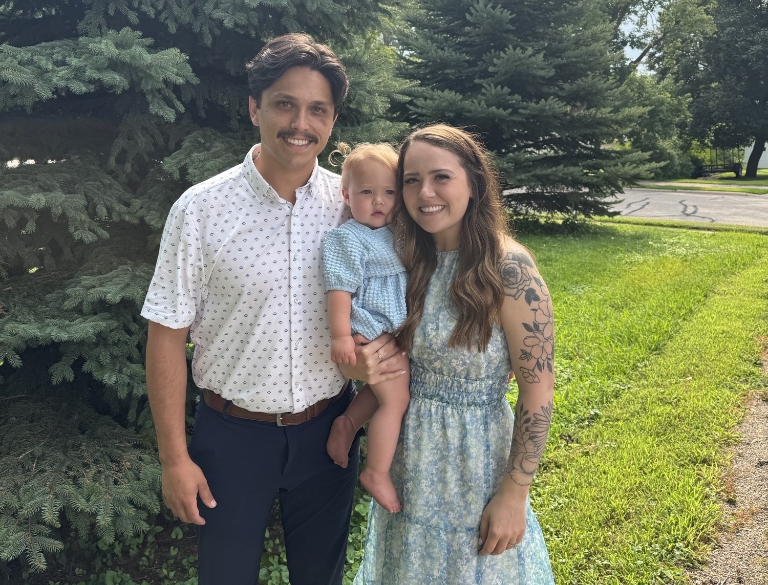 Sydni Smith smiling at the camera with her husband and daughter