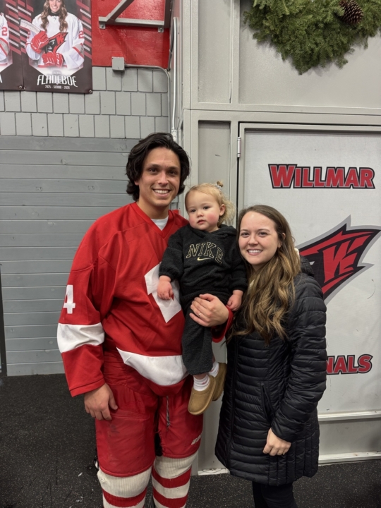 Sydni Smith smiling at the camera with her husband and daughter
