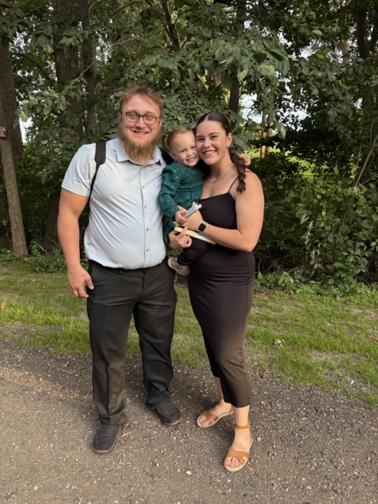 Rebecca Bohrer smiling at the camera with her fiancé and daughter