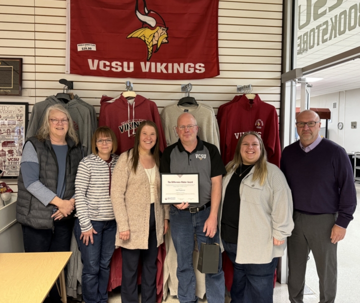 Todd and colleagues standing in bookstore with VCSU Vikings flag behind them