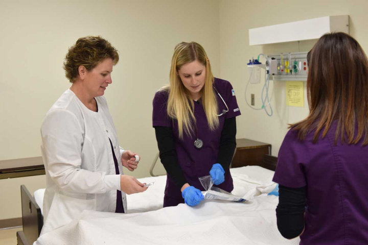 Students attending nursing courses on the campus of VCSU work with an instructor and a life-like doll. .