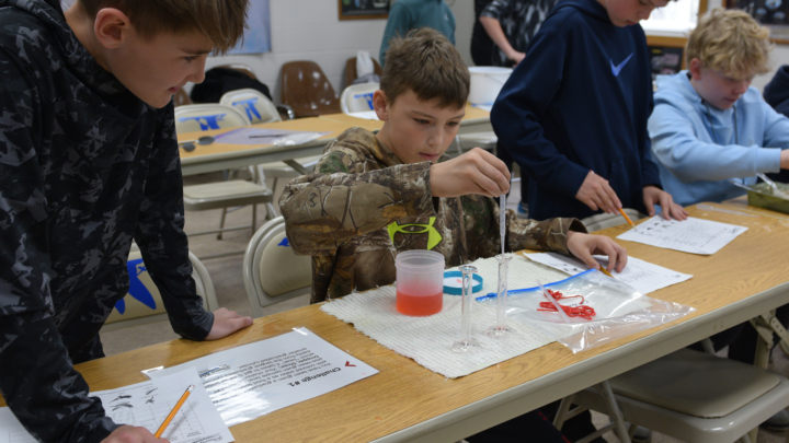Students working at desks with science equipment