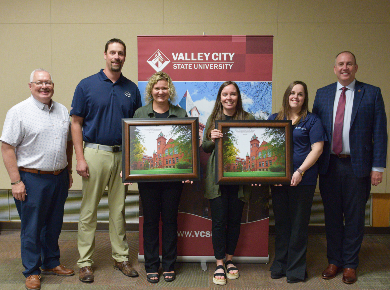 Representatives from FEI, Inc., and First Community Credit Union are pictured with VCSU photos they were given as a gift.
