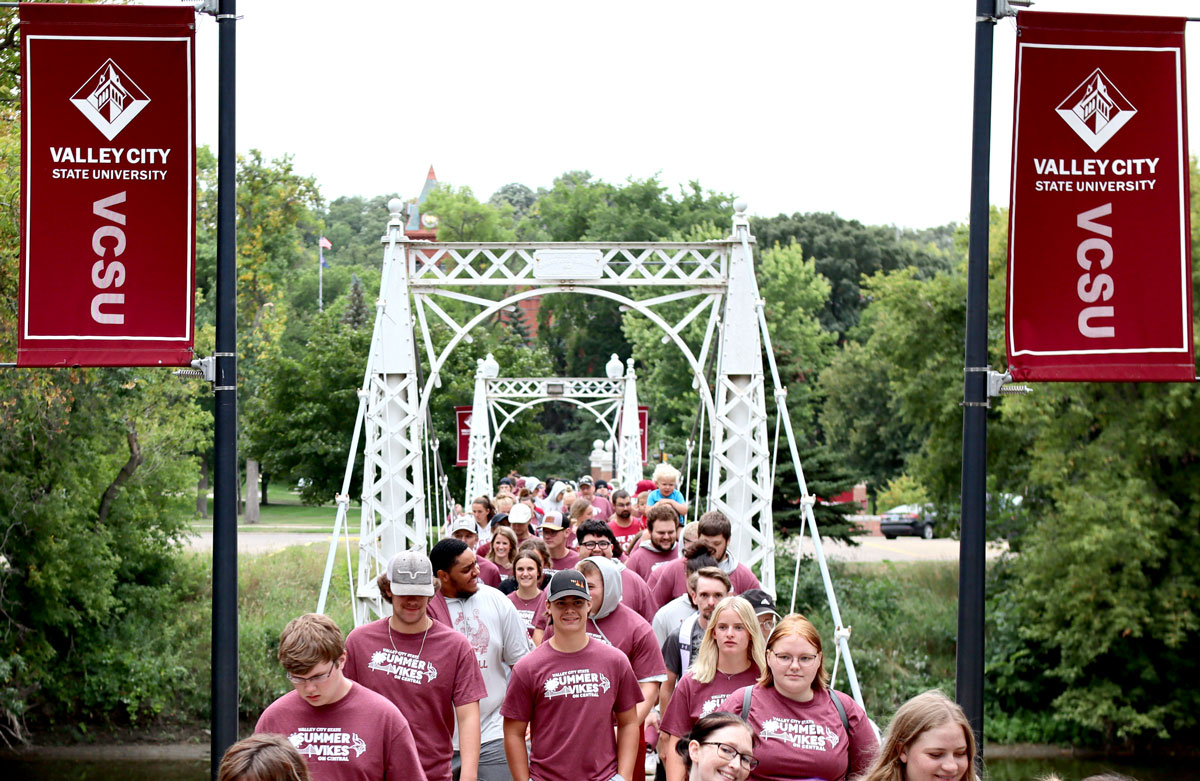 VCSU students walking across the footbridge on campus.