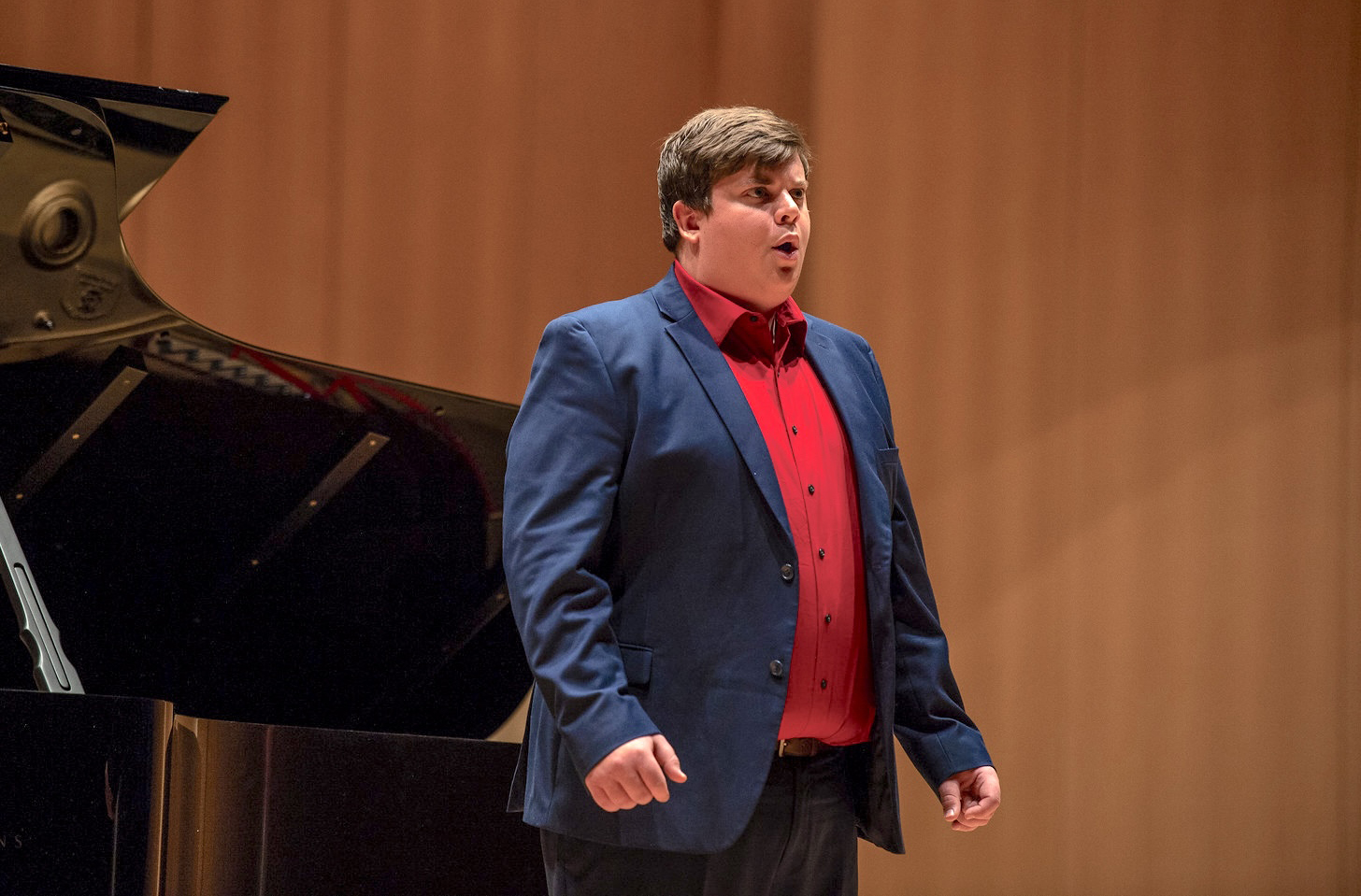 A VCSU male student sings in front of a black piano