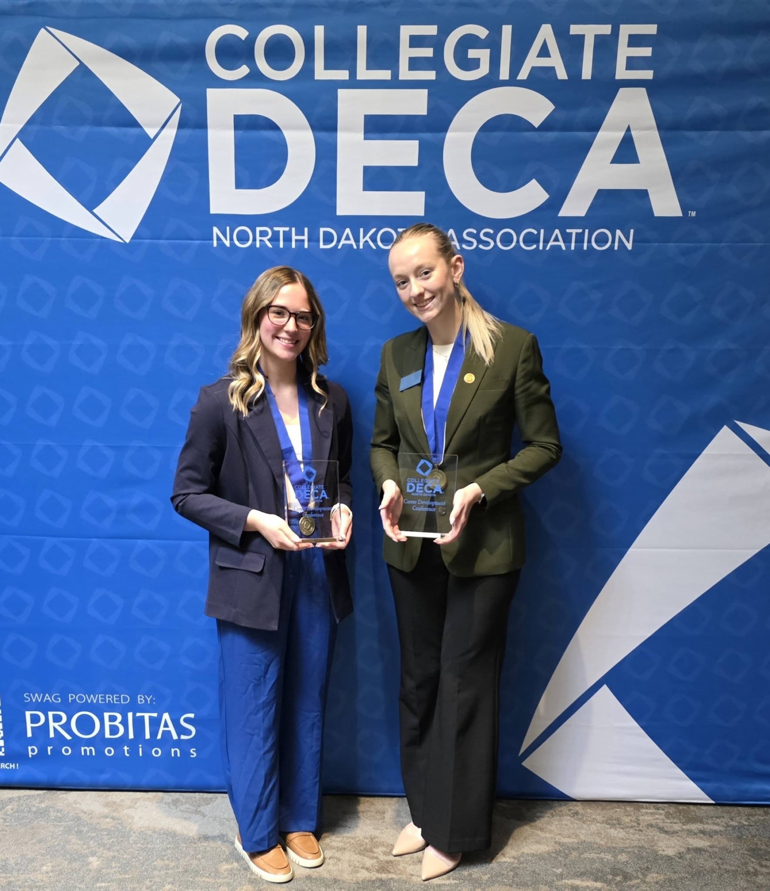 students holding awards in front of DECA sign