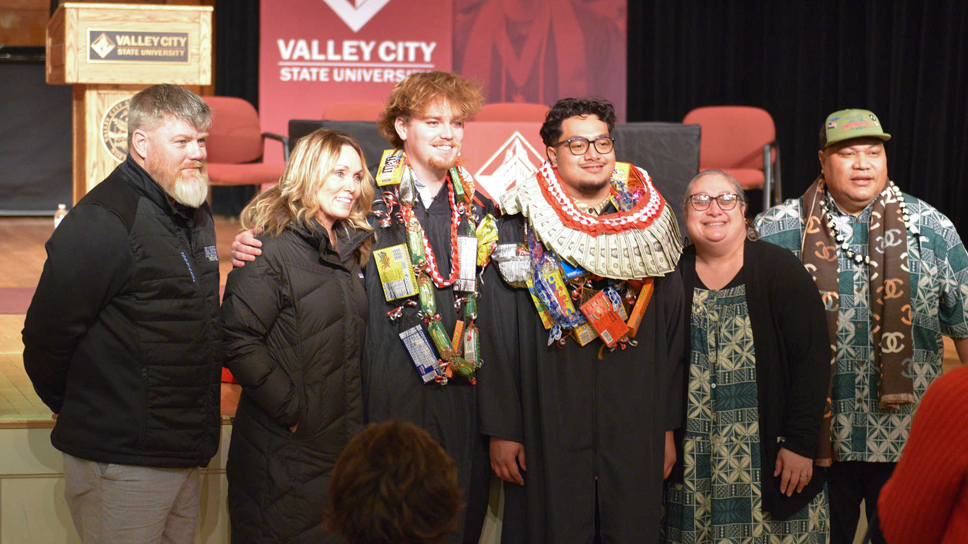 Two male graduates pose for a picture with members of their families