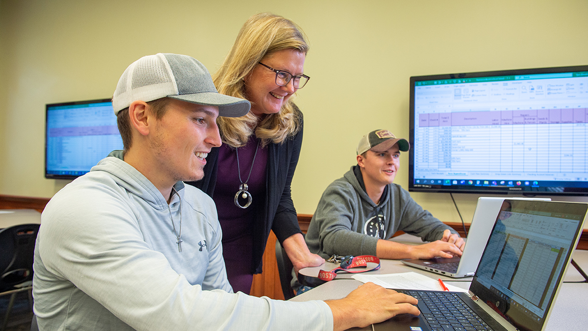 male business students receiving help from female professor