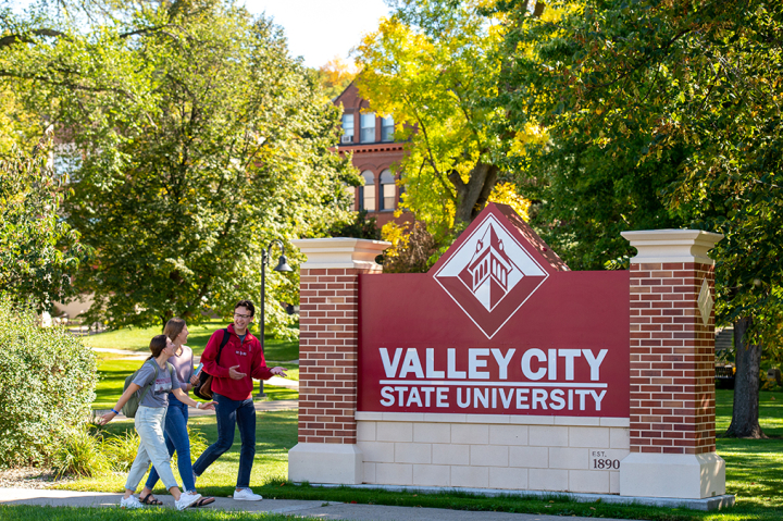 Three students walking on the front lawn of Valley City State University.