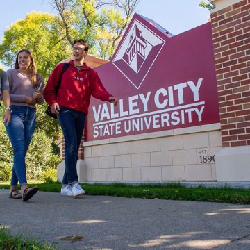 Three students walk near the Valley City State University sign