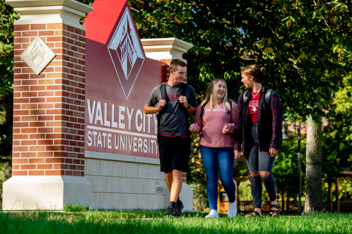 students walking outdoors by VCSU sign