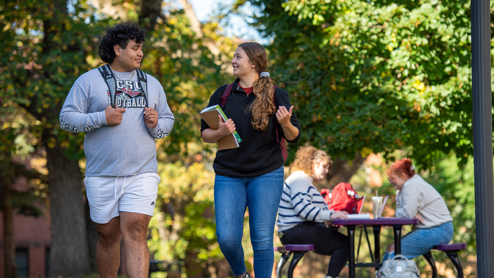 male and female student walking and talking outdoor campus