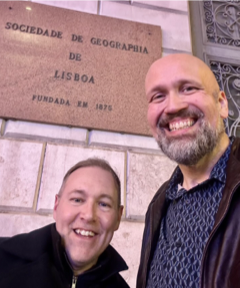 Anthony Dutton and Luis DaVinha posing in front of sign in Lisbon, Portugal