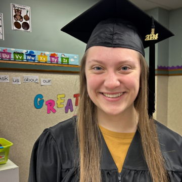 Jazmine Truax wearing cap and gown in her kindergarten classroom