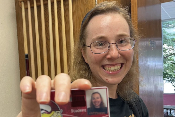 student holding student ID towards camera