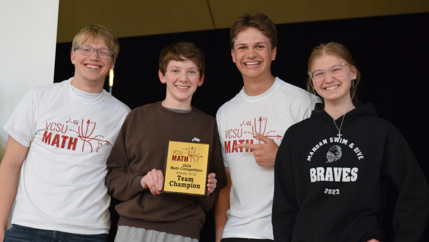 4 students hold a team champion plaque