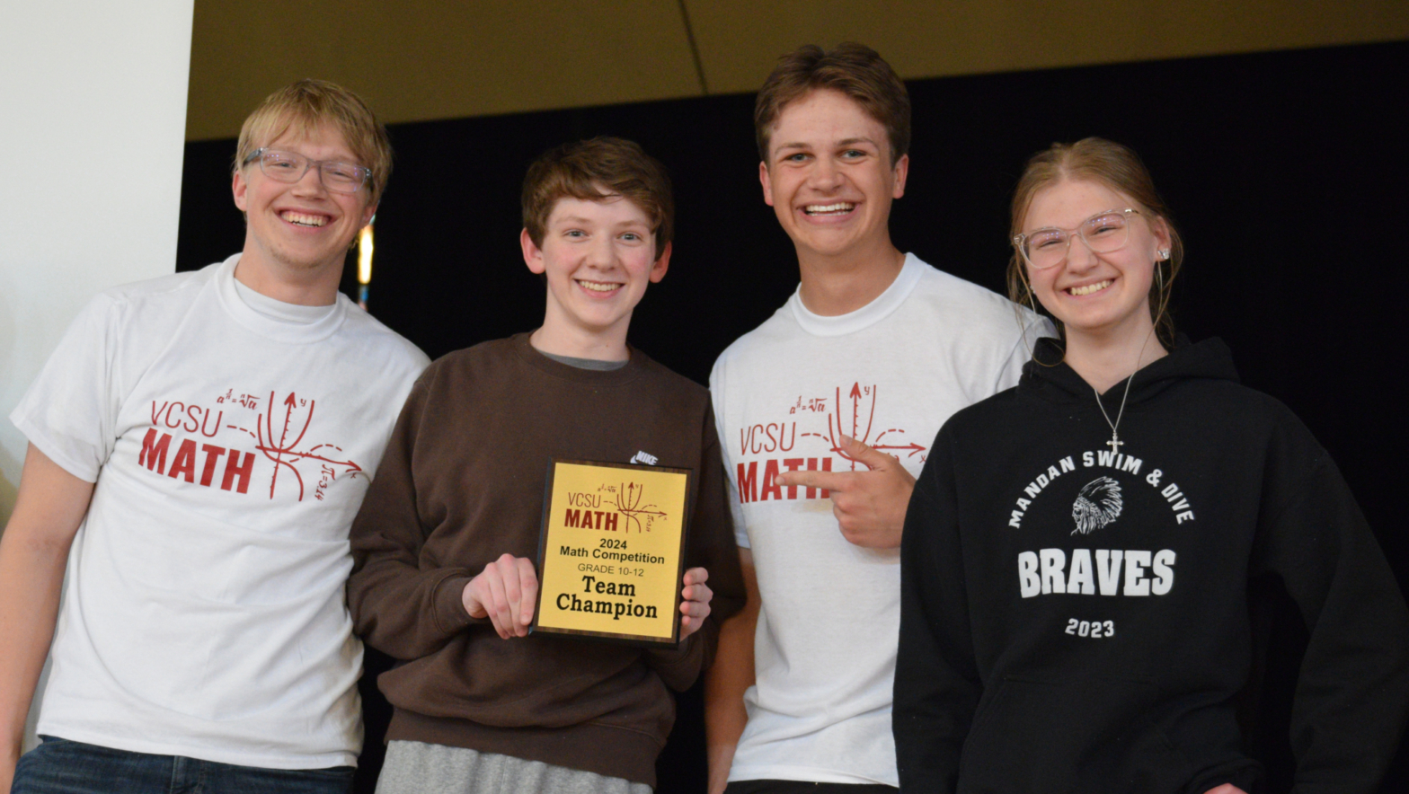 4 students hold a team champion plaque