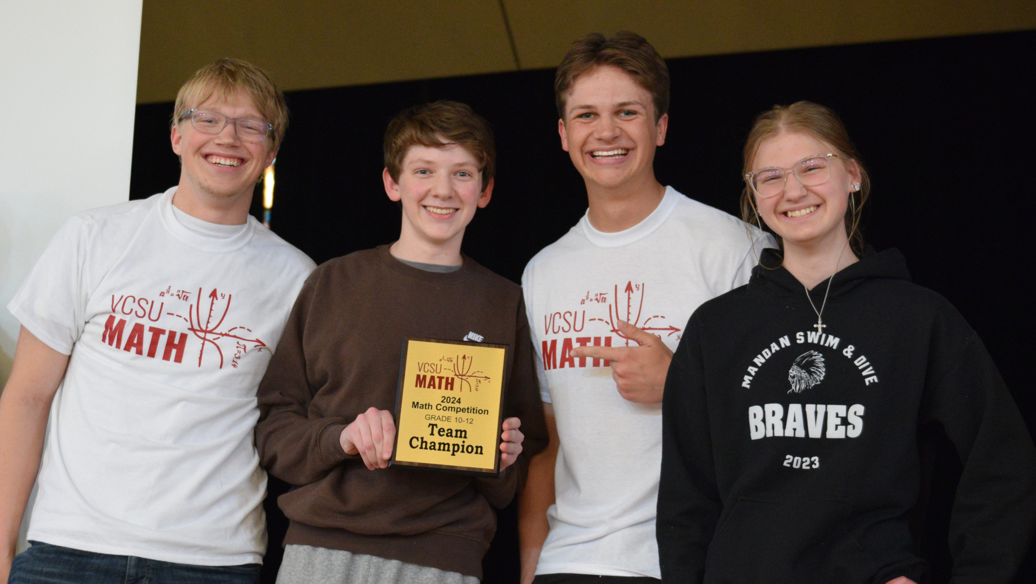 4 students hold a team champion plaque
