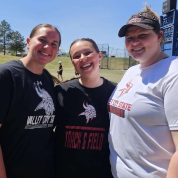 Megan Lahtonen smiling at the camera with two female VCSU students