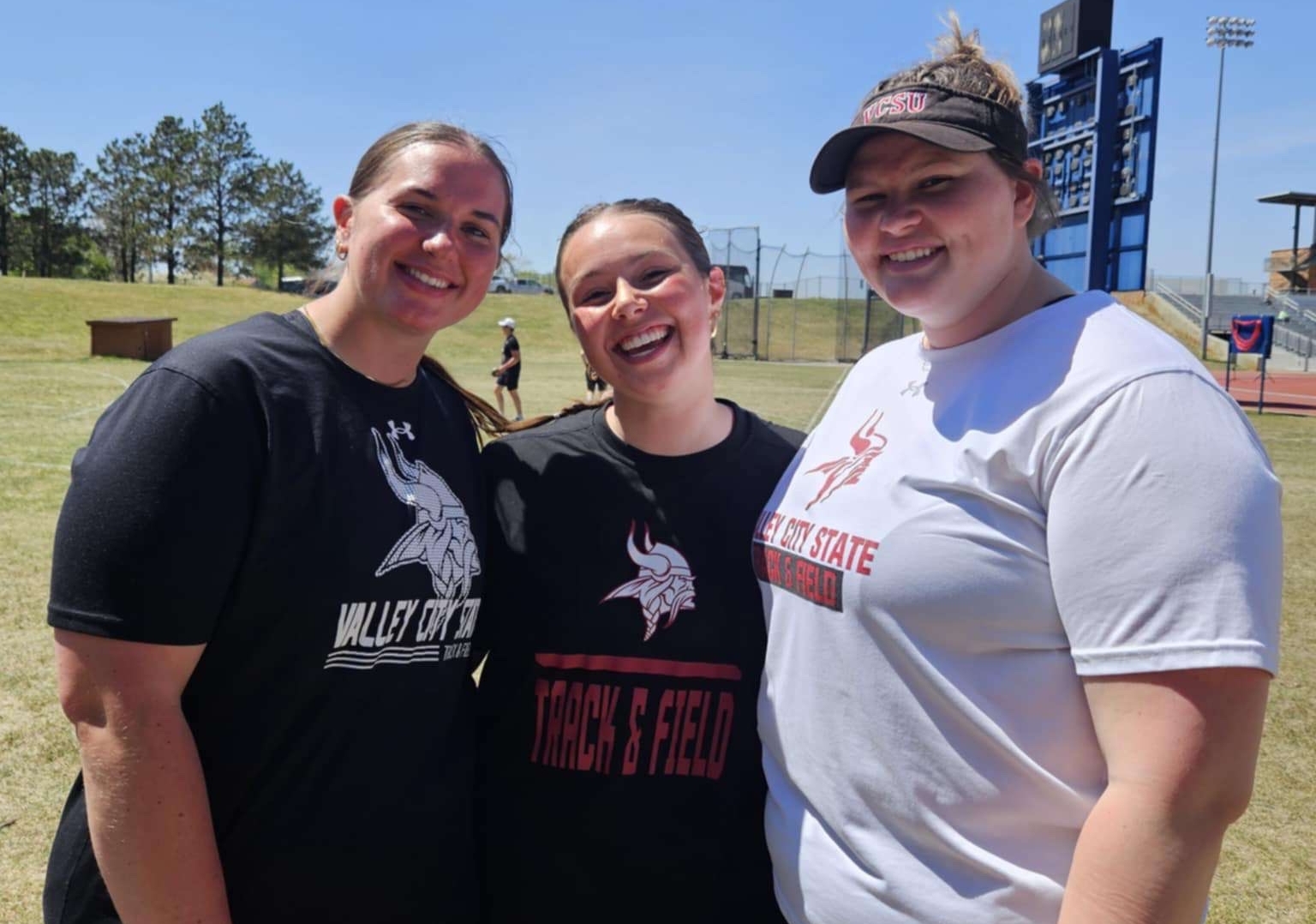 Megan Lahtonen smiling at the camera with two female VCSU students