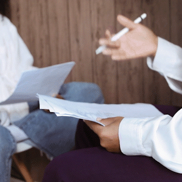 two people discussing with pens and papers