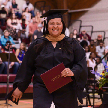 Riley Perryman in cap and gown with diploma in hand