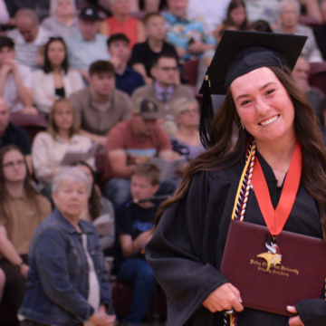 Saige Forseth in cap and gown with diploma at commencement
