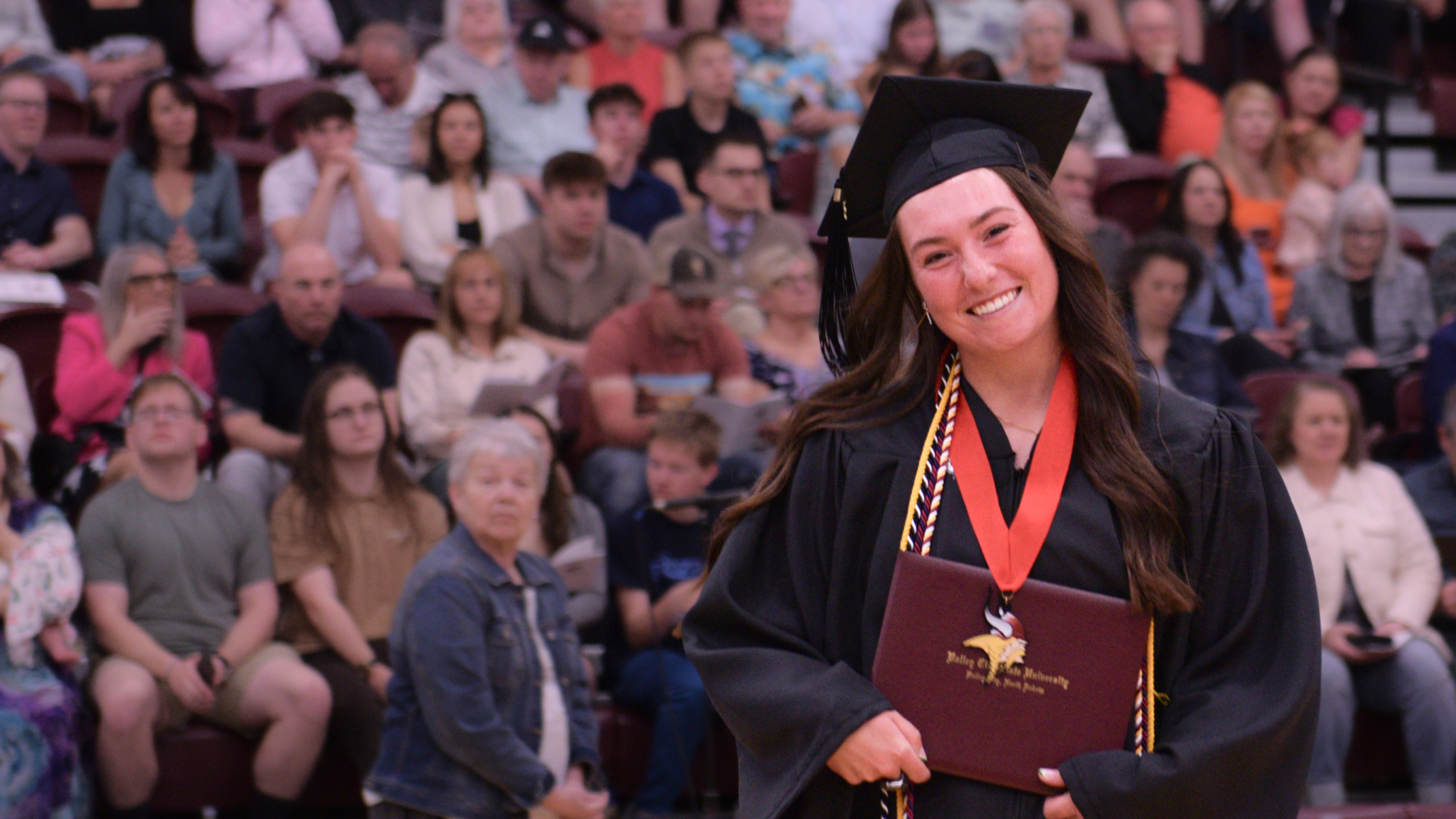 Saige Forseth in cap and gown with diploma at commencement