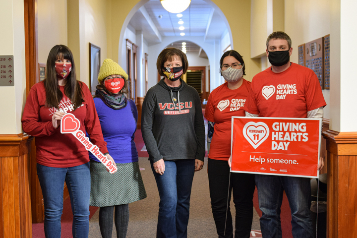 staff and faculty holding Giving Hearts Day signs