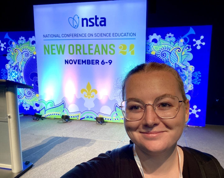 Kiecker posing in front for NSTA signage at conference venue